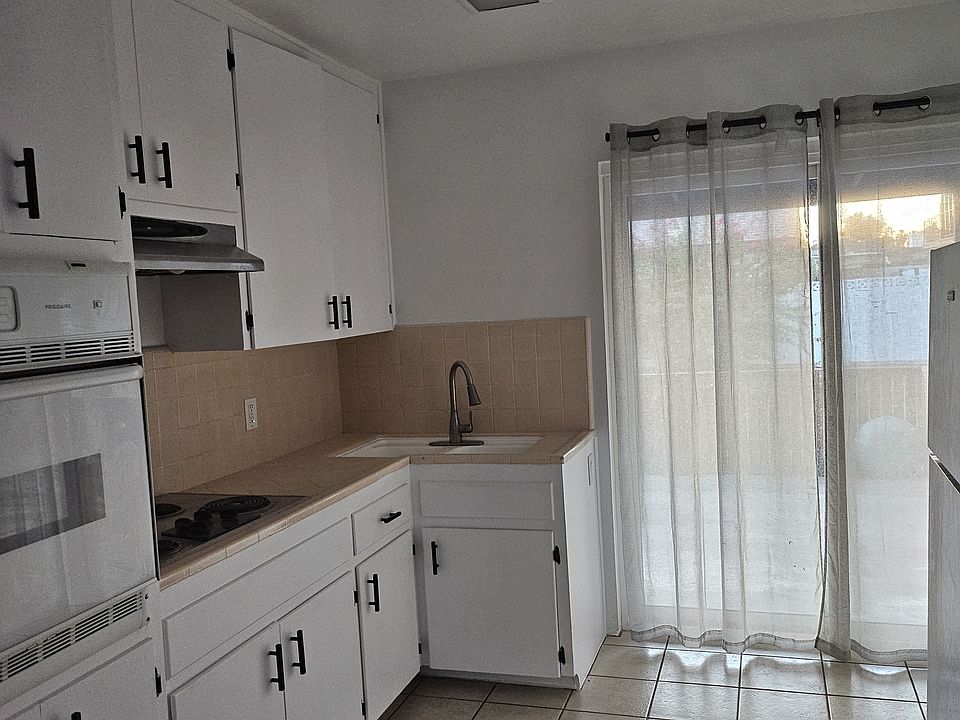 Kitchen with over, stove, sink and fridge.