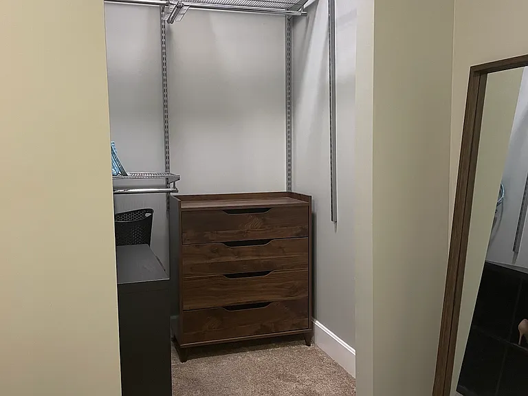 Walk-in closet with a closet system and dresser.