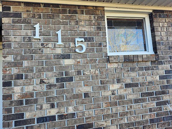 View of the nicely painted house number "115" affixed to the front entrance of the house; the designed bathroom window is to the right.