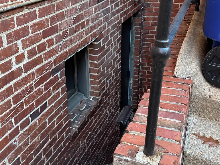 side of building by trash, recycling, and entrance to basement