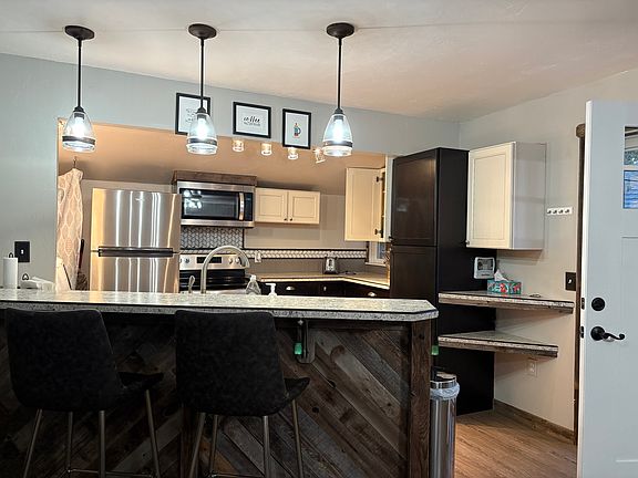 Kitchen with clean stainless appliances, bar seating for two.