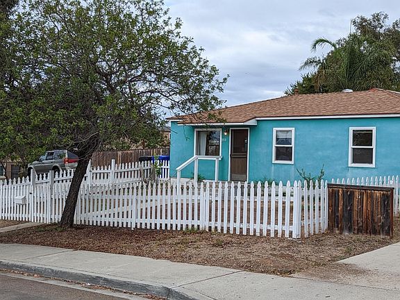 Front of the house from another view. Front yard is fully fenced off with multiple fruit trees in front.