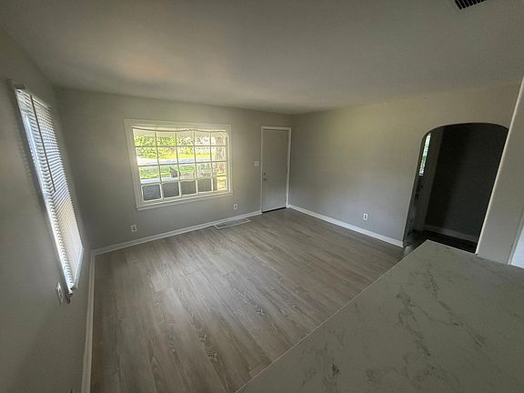 View of the living room from the breakfast nook. Note the large window that provides ample natural lighting, and the gorgeous arched frame for the hallway entrance.