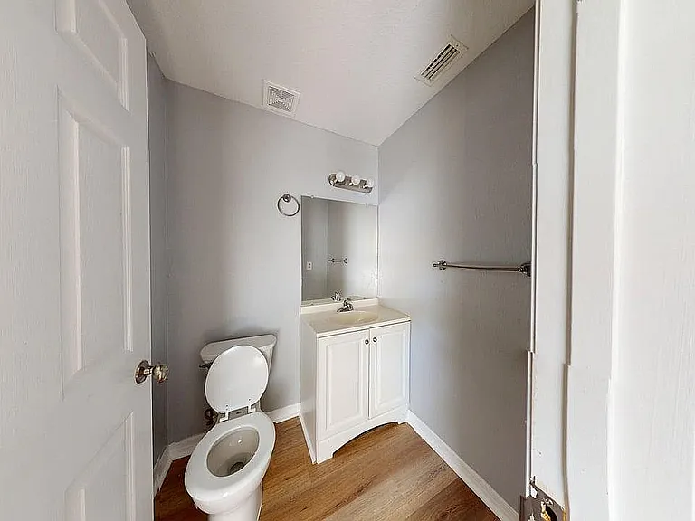 Charming bathroom with modern fixtures, stylish vanity, and sleek wood flooring, maximizing space and comfort.