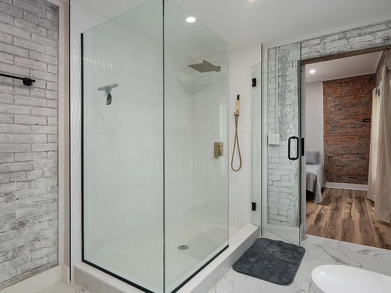 Spa-style bathroom featuring a frameless glass walk-in shower with rain head, tile flooring, and updated fixtures.