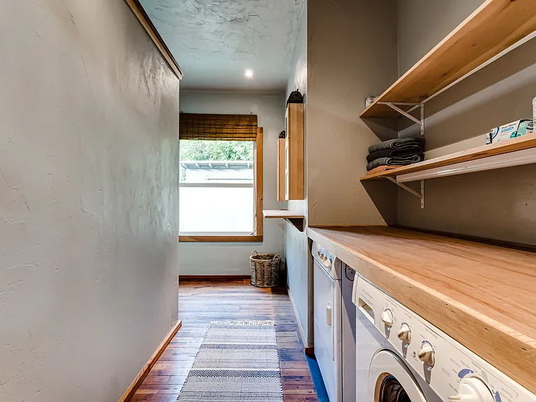 Galley style laundry room complete with washer and dryer. Lots of shelves and a very convenient counter top for folding.