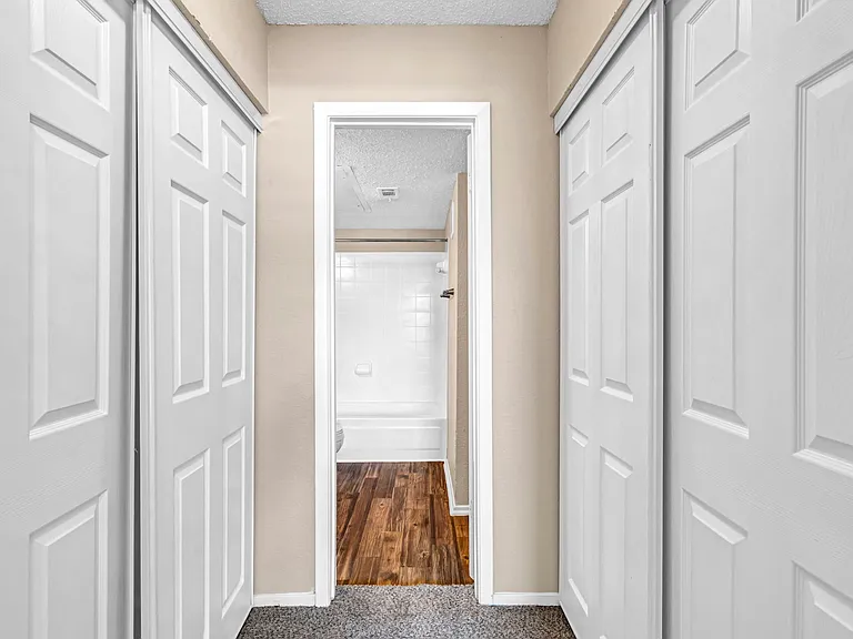 Hallway with double closets providing extra storage and functionality.