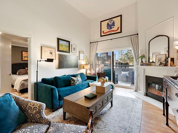 Living room with 12 Ft. ceilings and fire place. Balcony doors have been replaced with soundproof doors.
