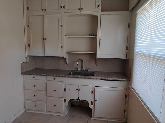 Kitchen has granite countertop and lots of storage in shelves and cabinets.