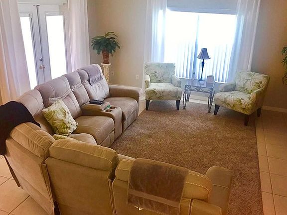 Large living room with patio doors out to the pool and large window making the house lovely and bright. Tiled floor.