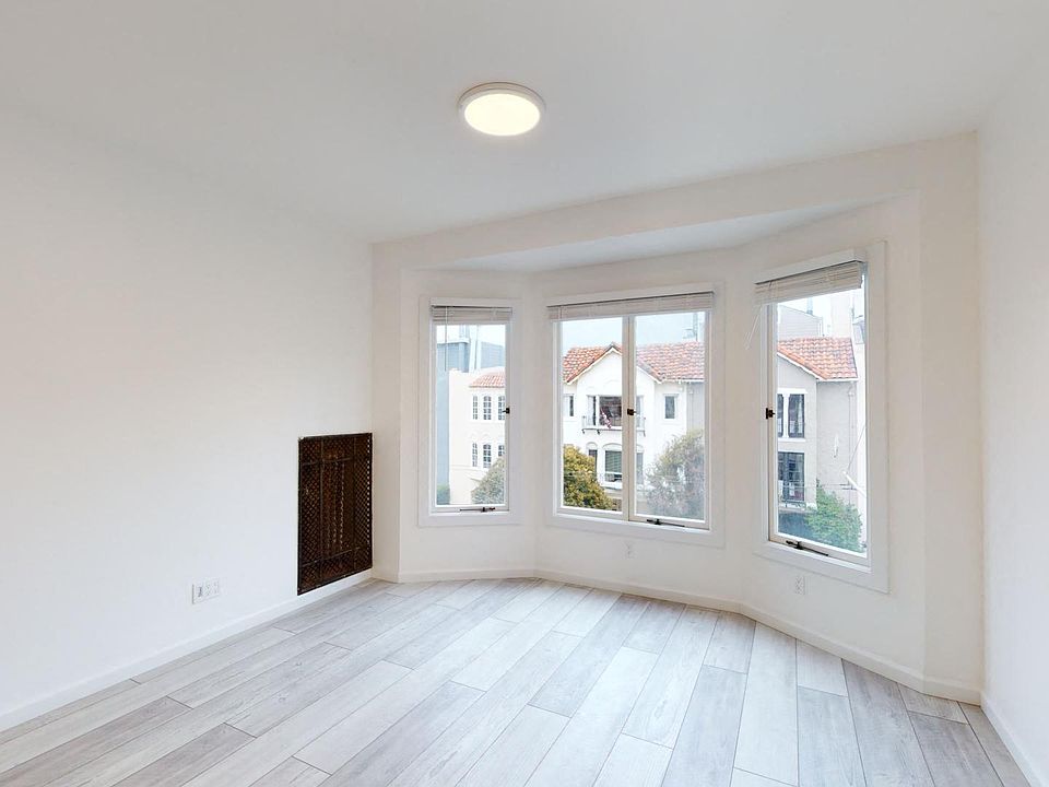 Sunlit room with a large window and a wood-like flooring