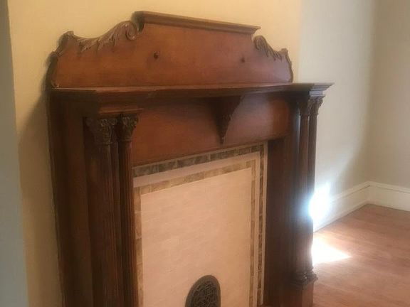 One of three fireplaces in the house. These are used as vents for forced air heat. This one is in the living room. There is crown molding in this room and hardwood floors. Great light, as this house faces south