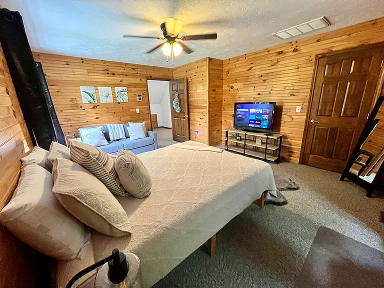 North facing bedroom has a queen bed, ceiling fan, sofa, designated work space, desk lamp, desk fan, Roku steaming TV, built in drawers, and walk-in closet with a full length mirror.