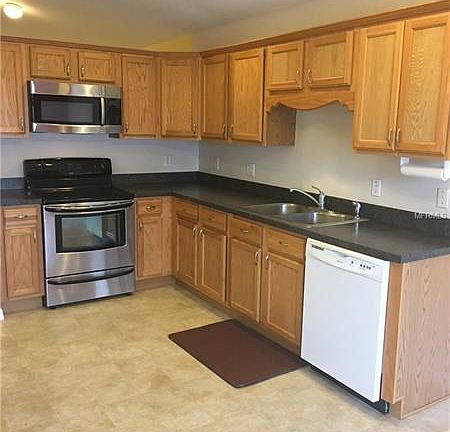 Kitchen showing recessed lighting, Wood cabinets, microwave, range, dishwasher, and vinyl flooring