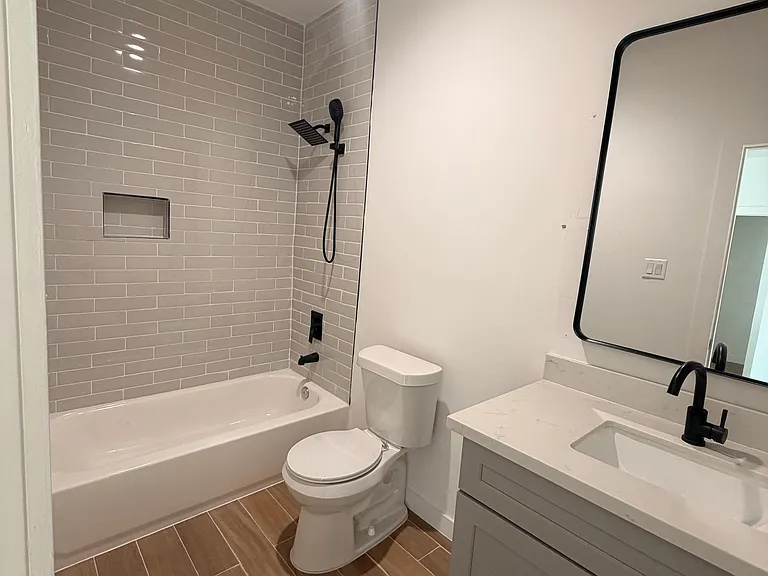 Modern bathroom featuring a tub/shower combination, quartz vanity, and contemporary finishes, offering a clean and com