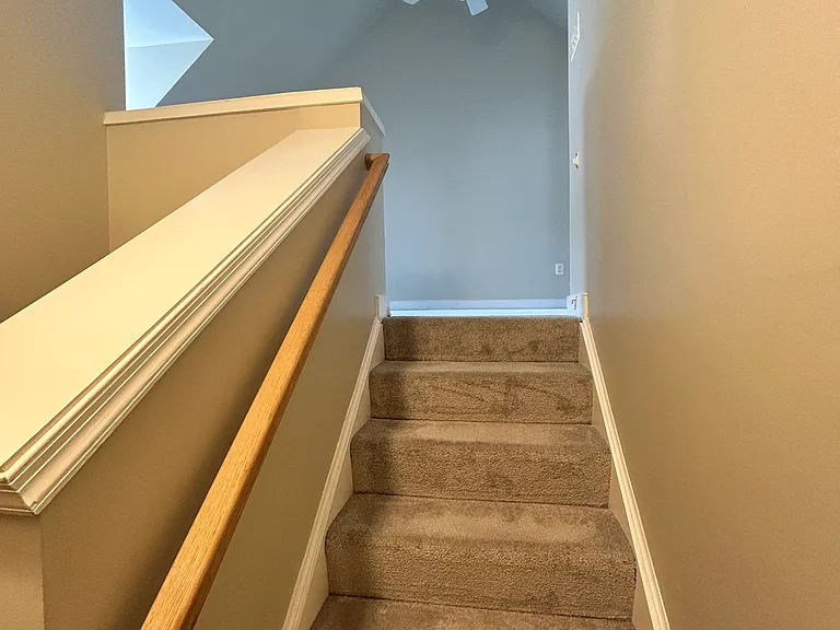 Stairs to third floor from landing. The door to this bedroom is at bottom of the stairs.