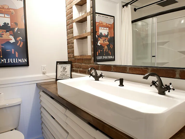 Custom main bath suite. Features: Sliding mirror for hidden storage, built in recessed shelving, dimmable lighting, double sink basin, linen closet, and oversized tub/shower combo with custom showerheads.