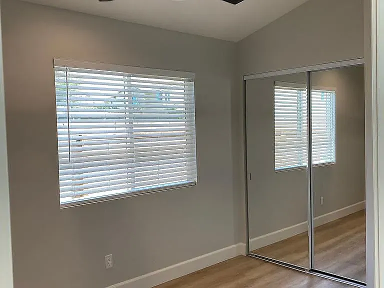 bedroom #1 has a ceiling fan in black, mirrored closed doors, and vinyl plank flooring.