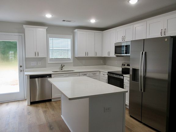 Kitchen w/many soft close cabinets, island, stainless steel fridge & gorgeous veined quartz countertops