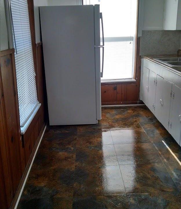 GE Fridge, polished tile flooring with a window facing the front and one to the side of the apartment. The new kitchen windows now have curtains.