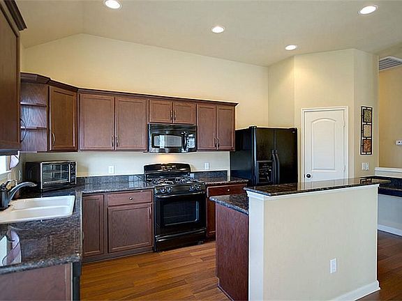 Natural light brightens the space while granite countertops, wood laminate flooring, and dark stained cabinets combine to create a gorgeous gourmet kitchen.