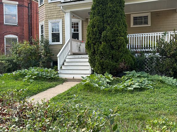 Large front yard with verdant hedges and lush lawn.