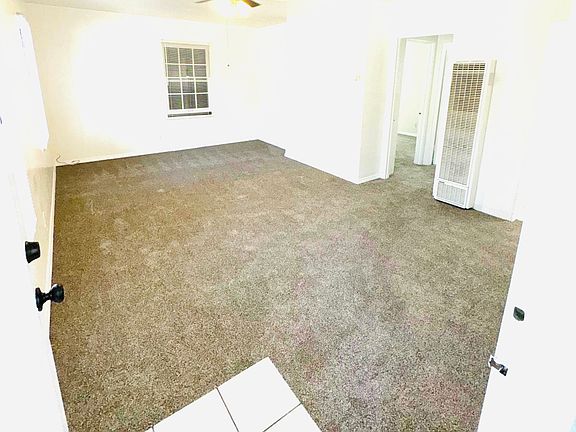 Spacious Living room with new light grey carpet, wall heater and ceiling fan.