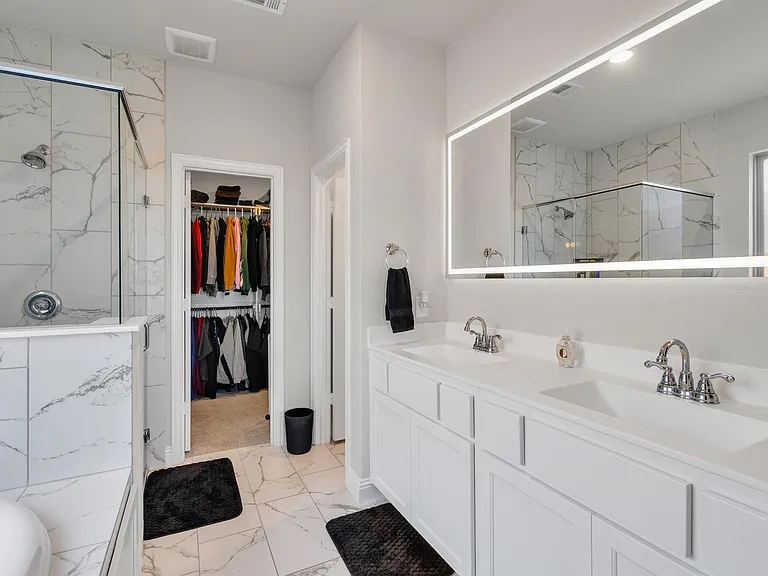 Bathroom featuring a dual vanity with white cabinetry, integrated sinks, and chrome fixtures