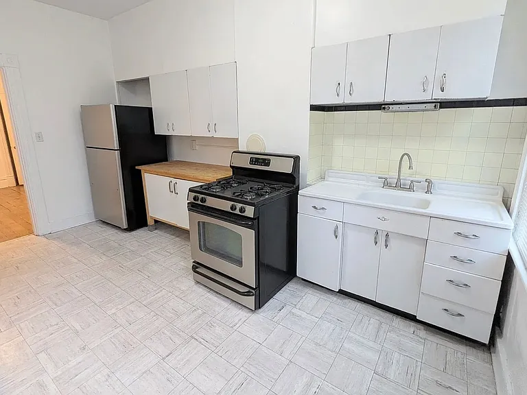 1st floor Kitchen with wonderful light, featuring refurbished vintage metal cupboards (upper section & below sink), as well as 2 spacious IKEA storage units w/wooden, butcher block counter tops, gas stove, refrigerator, the door leads to the garden