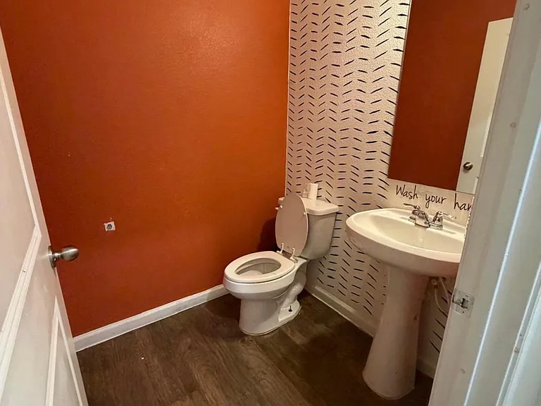 Half bath with pedestal sink, mirror, and durable flooringideal for guests and convenient day-to-day use.