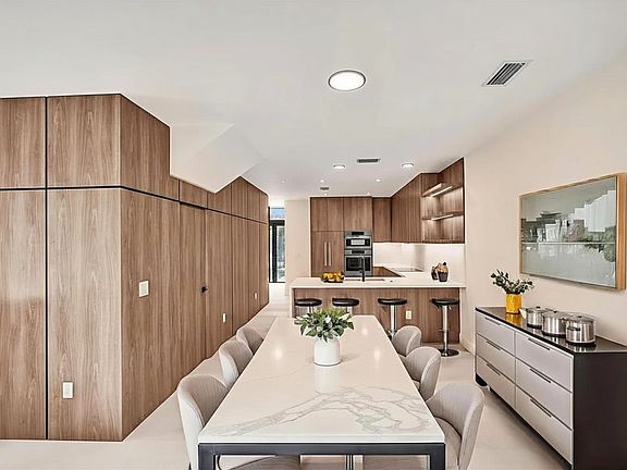 Luxury kitchen and dining room area with Bosch appliances, wood finish, LED lights. Ideal for entertaining or a private at home relaxation while enjoying your open space and pool view.