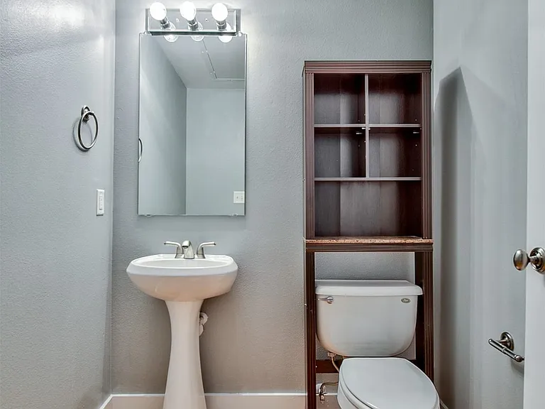 Bathroom featuring a pedestal sink, wood-finish flooring, and a mirrored vanity light fixture