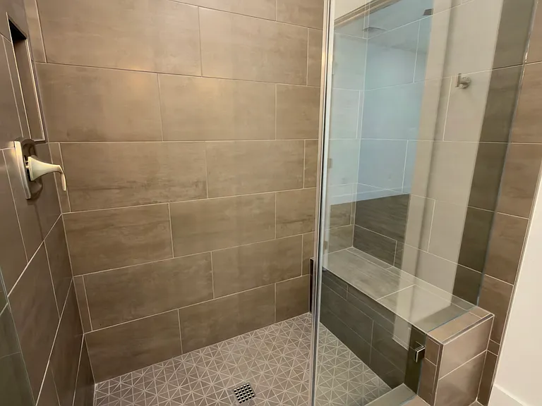 Spacious seamless glass shower with full-height tile and a built-in bench, creating a luxurious, spa-inspired retreat.