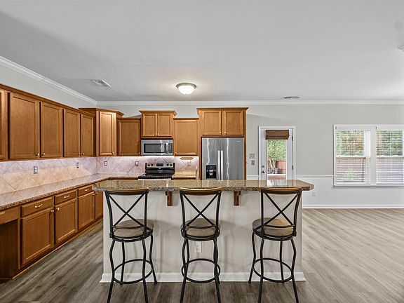 The kitchen, featuring abundant storage and spacious counter areas, is designed for both cooking and socializing, with a large island and barstools that provide the perfect setting for gathering with family and friends.