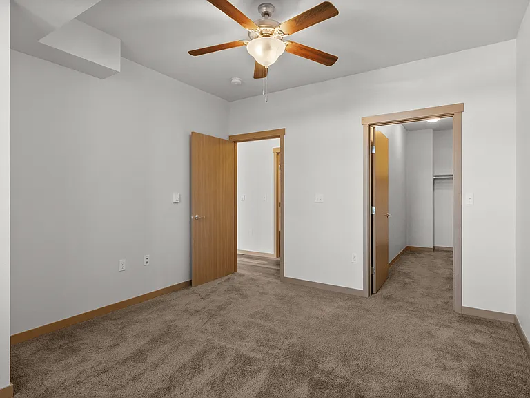 Charming bedroom with plush carpet, ceiling fan, and walk-in closet. Charming bedroom with plush carpet, ceiling fan, and walk-in closet.