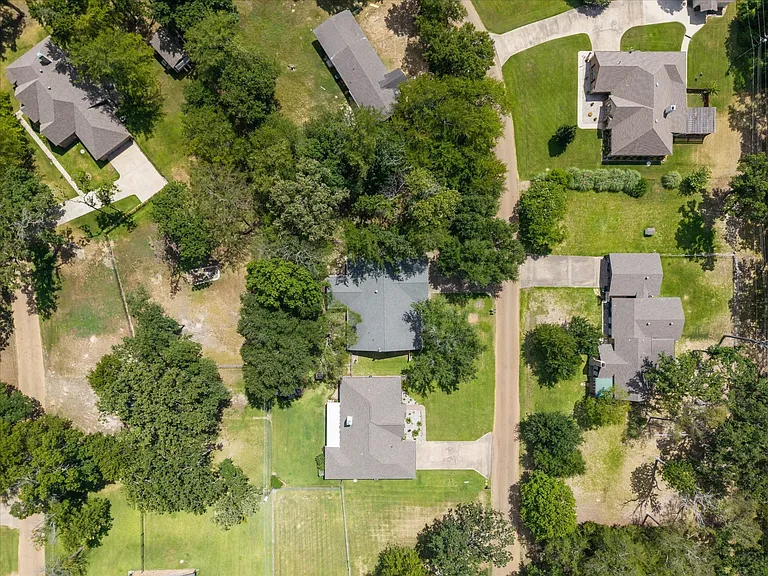Aerial perspective showcasing multiple properties, each featuring a pitched roof, mature trees, and a concrete driveway