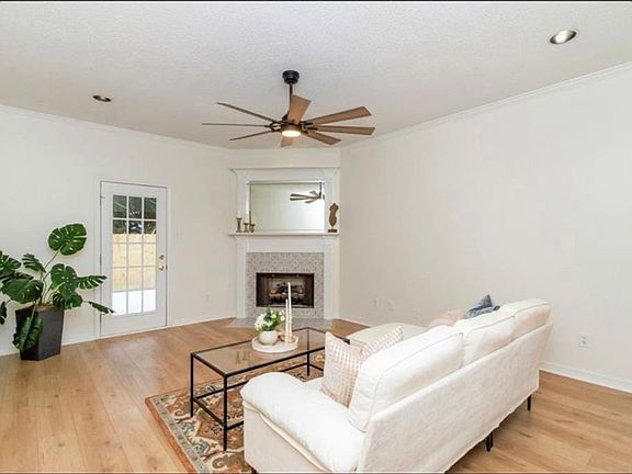 Living room with crown molding, light wood-type flooring, and ceiling fan