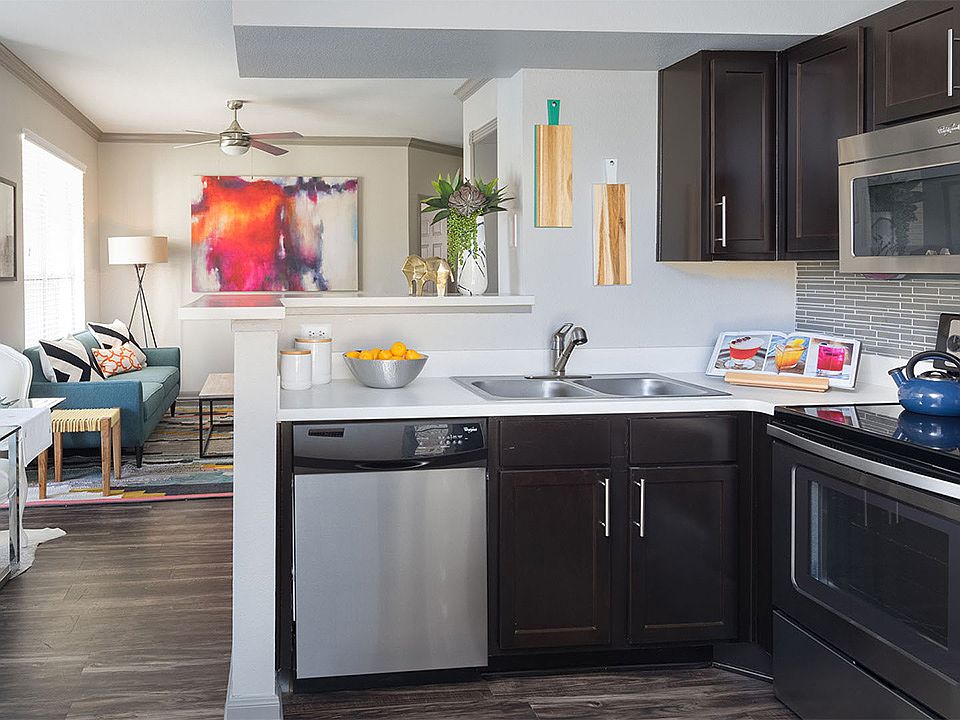 Apartment Kitchen with Stainless Steel Appliances, Dining and Living Room with wood floors.