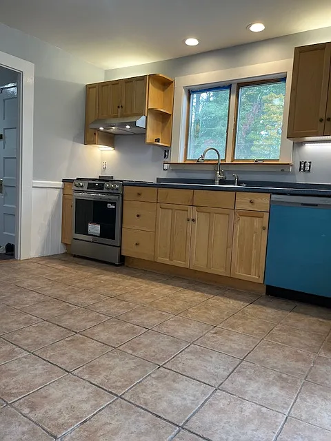 Kitchen with new dishwasher and new gas stove.
