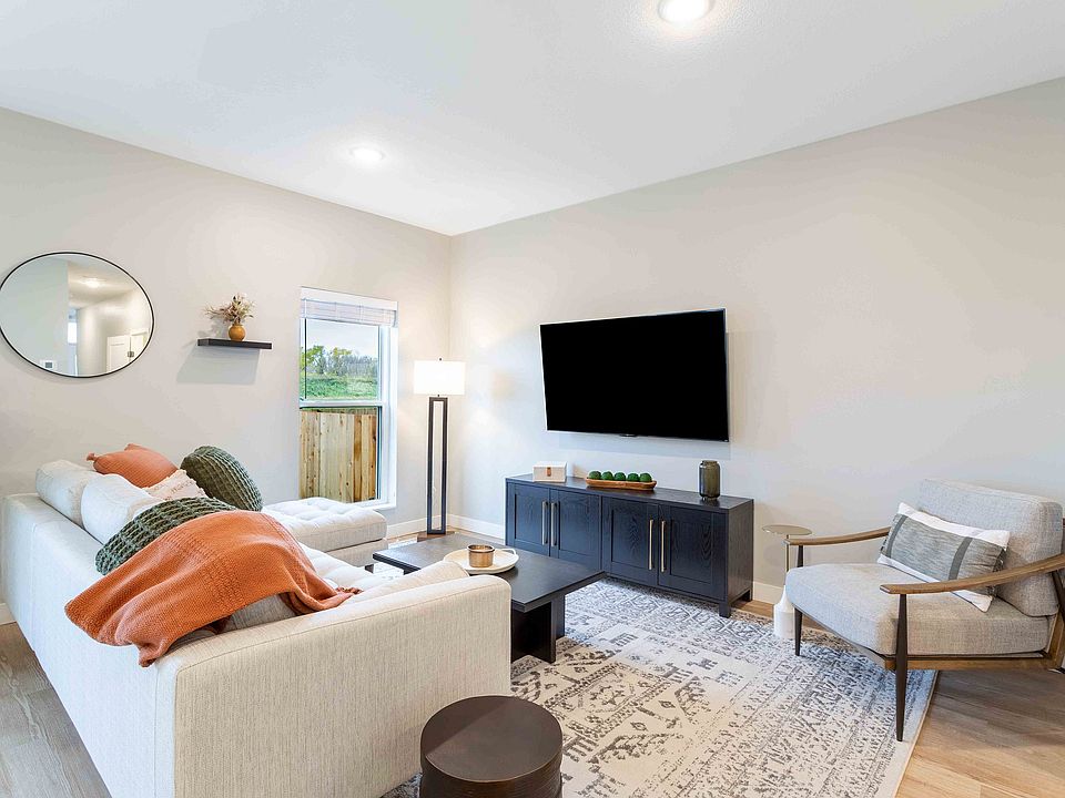 Bright and inviting living room with a cozy sofa, stylish accent chair, modern decor, and large flat-screen TV, ideal for relaxation and entertainment.