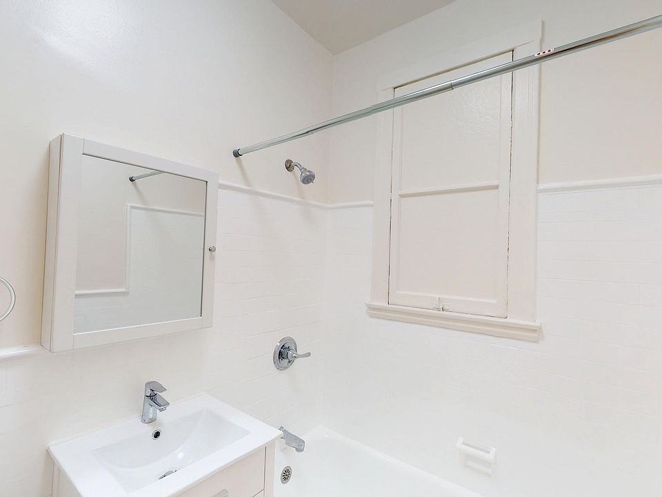 Clean, minimal bathroom featuring a bathtub, modern sink, wall mirror, and a shower with a glass rod on tiled walls.