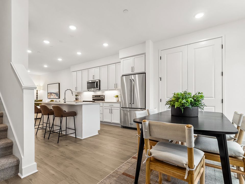 A modern, open-concept kitchen and dining area with white cabinets, stainless steel appliances, and