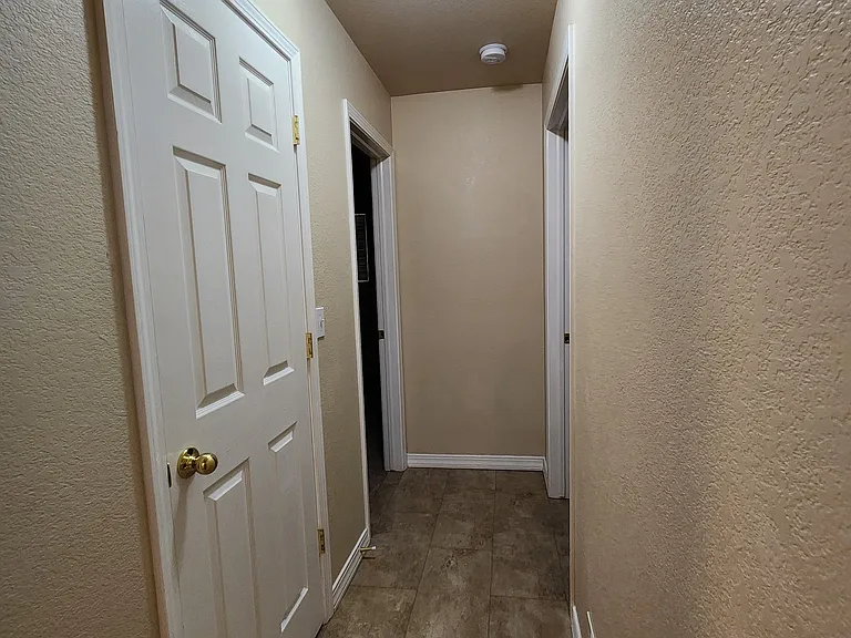 View halfway down the hallway from Entry Way to Bedrooms. Linen closet door on left. At end of hall, Master Bedroom on the Right, 2nd Bedroom with Private Bathroom on the Left.