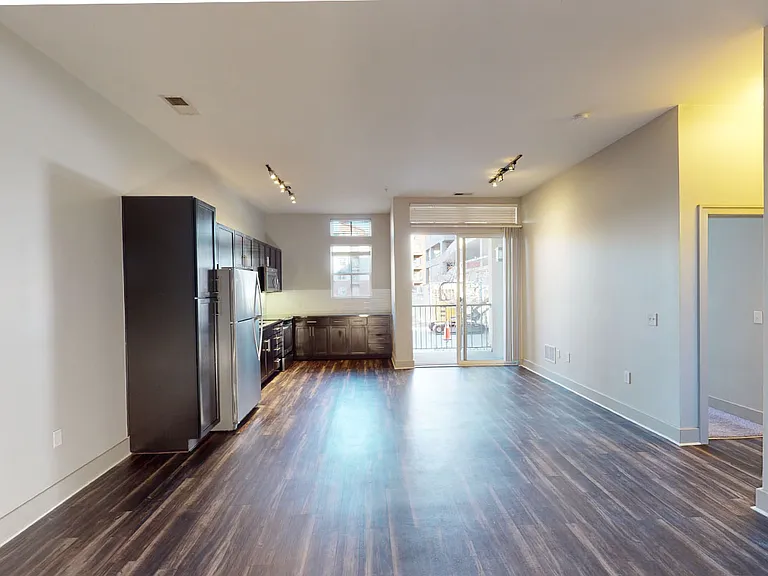 Apartment kitchen with stainless steel appliances, dining and living room with wood-style flooring and patio or balcony.