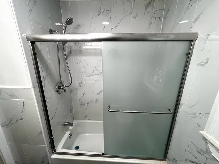 The new bathroom features a glass sliding door that is clouded for privacy and a brand new tub and shower!