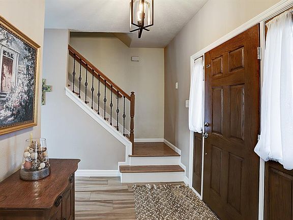 The foyer of this home has the recent addition of wood like tile floors, wrought iron spindles, and light fixtures. All baseboards are new and there are wooden stairs.