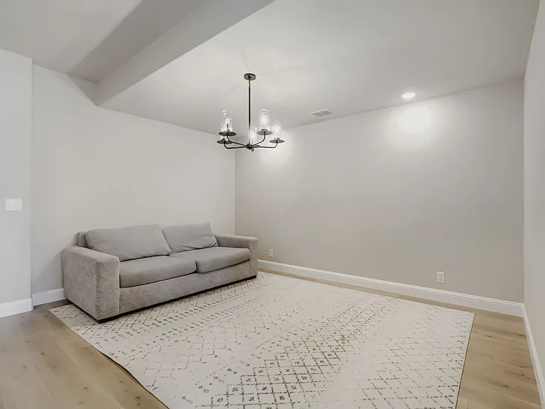 Spacious room featuring wood-finish flooring, a contemporary chandelier, recessed lighting, and crisp baseboards
