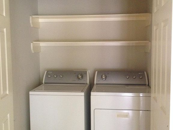 Laundry room next to kitchen with storage and included washer and dryer.