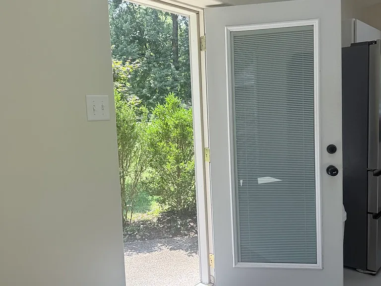 Front door into the property looking out at shrubs around patio.