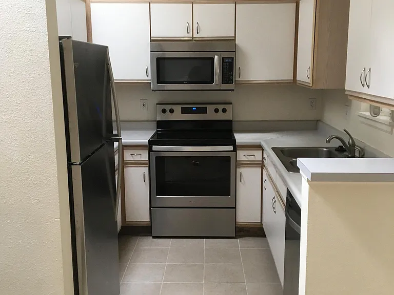Kitchen with new stainless steel appliances and tile.